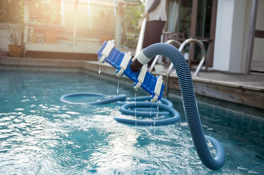 A pool vacuum head and hose being drawn out of the water