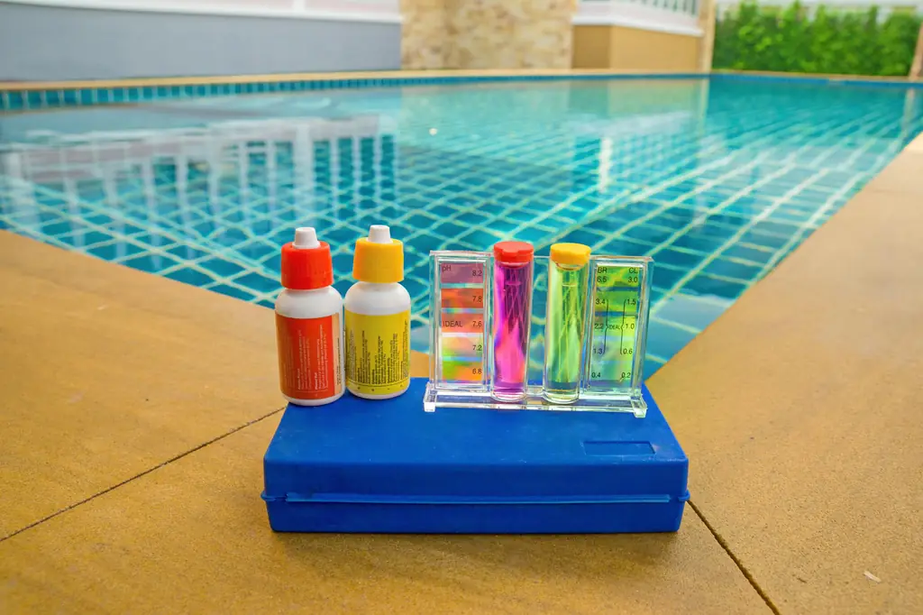 A pool water test kit with pH and chlorine vials at the side of the pool